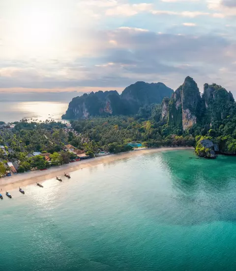 Panoramic aerial view of the beautiful Railay beach, lush rain forest and emerald sea during morning sunrise without people