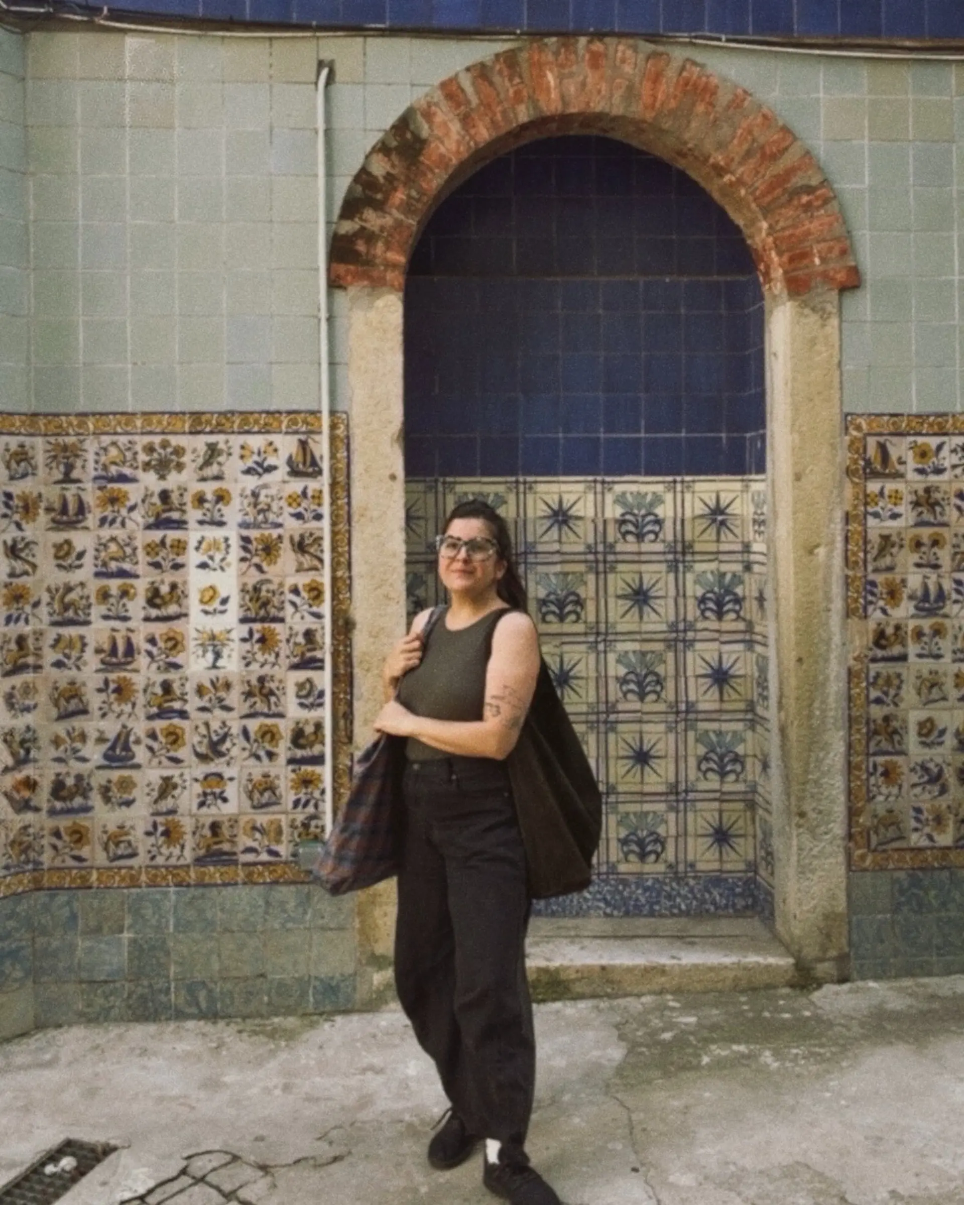 Globetrotting Art Director Emily in front of traditional blue and yellow azulejo tiles and a brick archway in Lisbon, Portugal