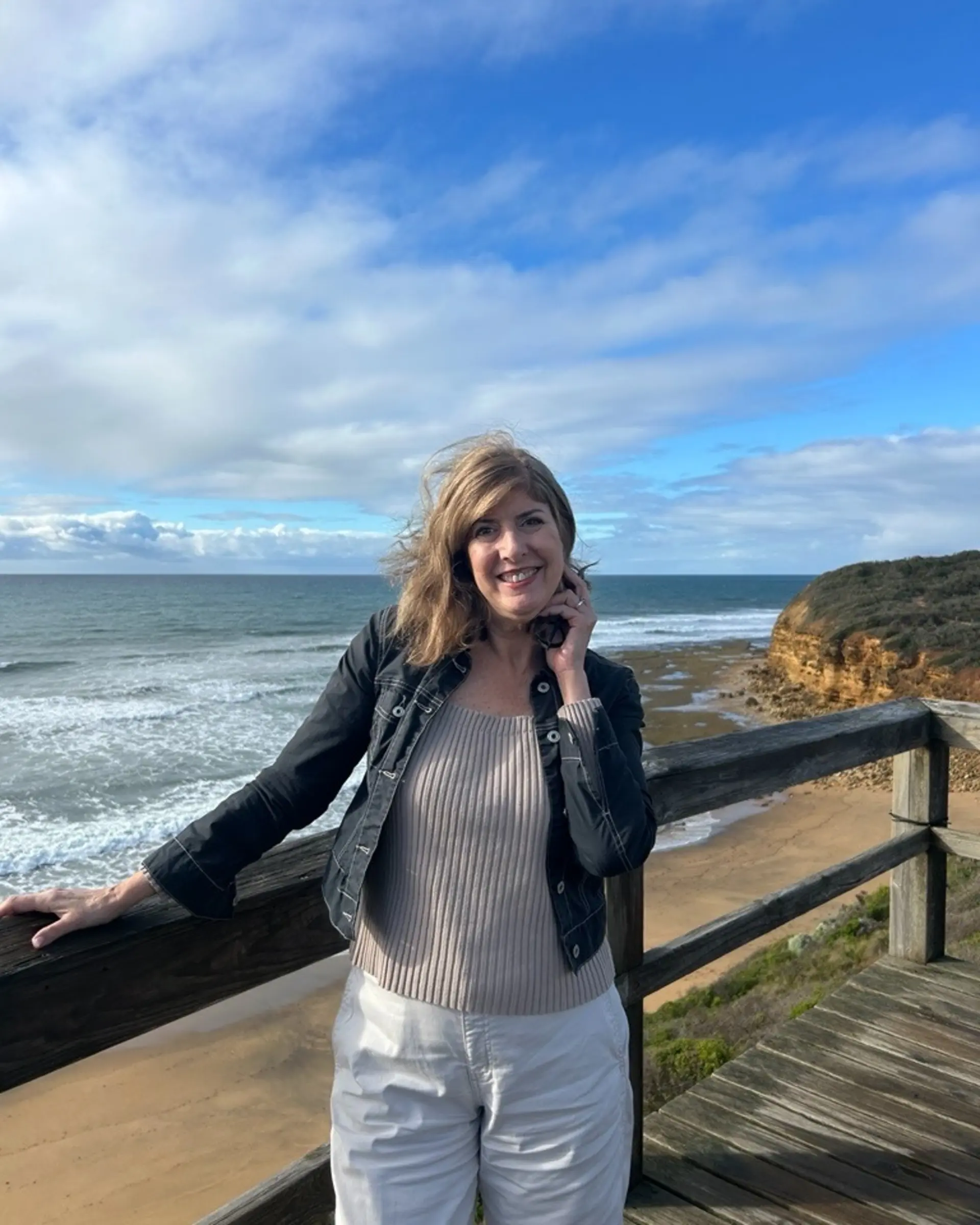 Globetrotting Partnerships Director Lori on a coastal lookout above a sandy beach and cliffs along the Great Ocean Road, Australia