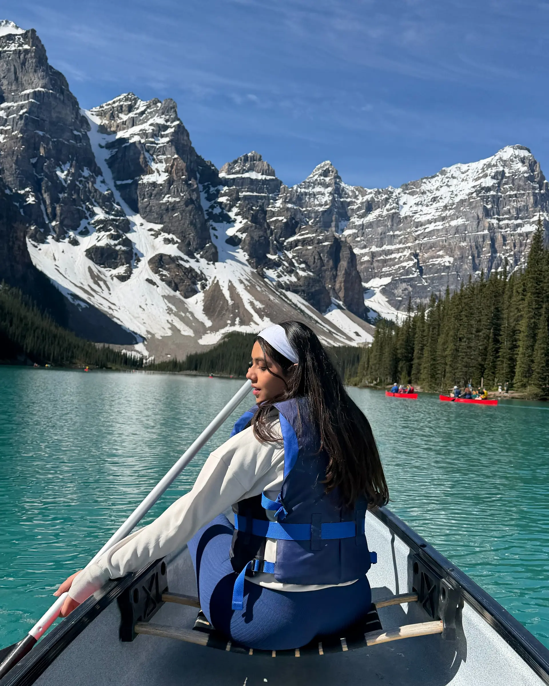 Globetrotting Content & Creative Coordinator Navya canoeing on turquoise Moraine Lake beneath snow-capped peaks in Banff National Park, Canada