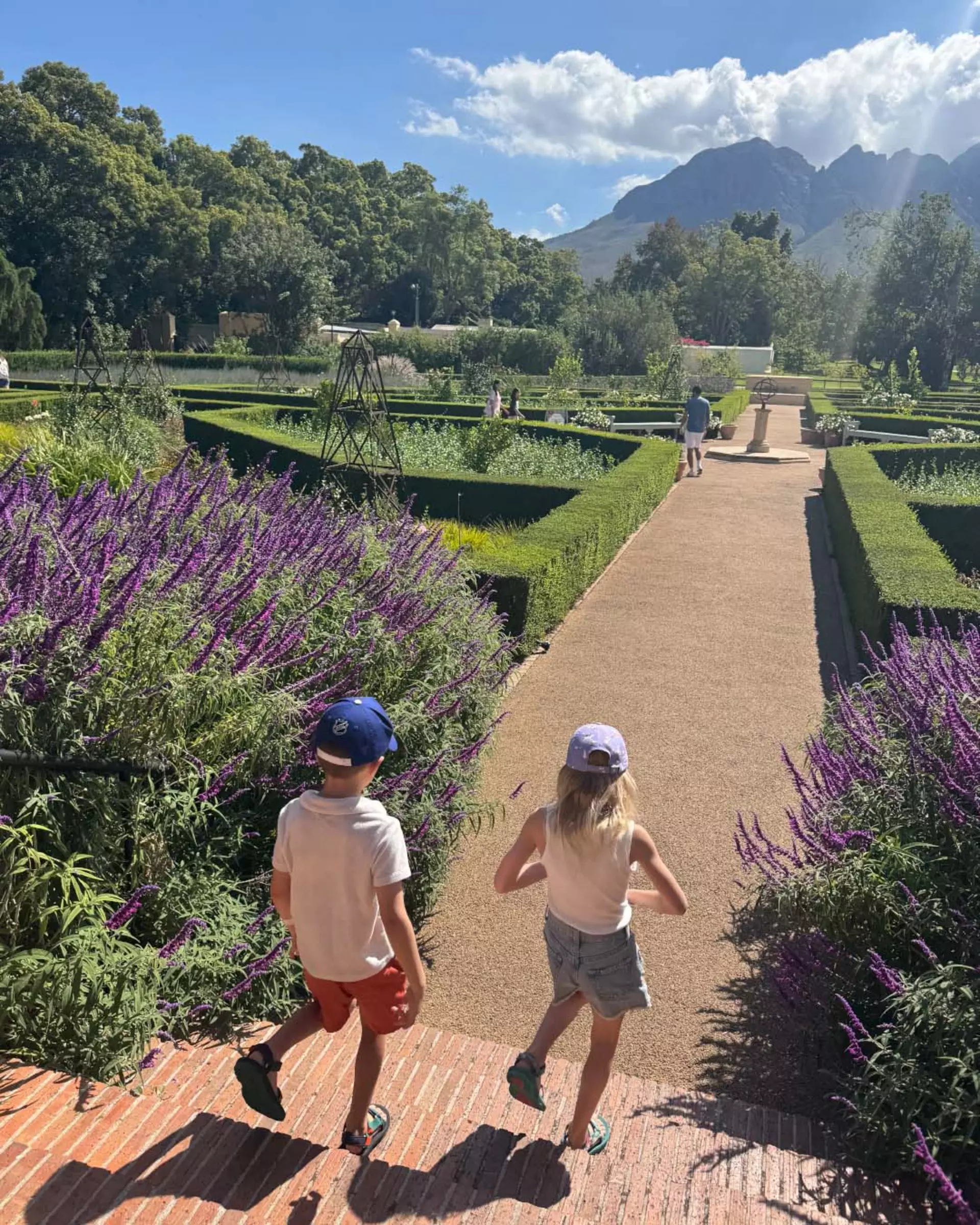 Two children walk through a manicured garden in South Africa