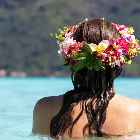 Beautiful woman wearing colorful flower crown while on a tropical island vacation in Bora Bora near Tahiti in French Polynesia 