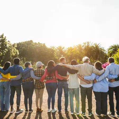 A group of employees stand with arms joined