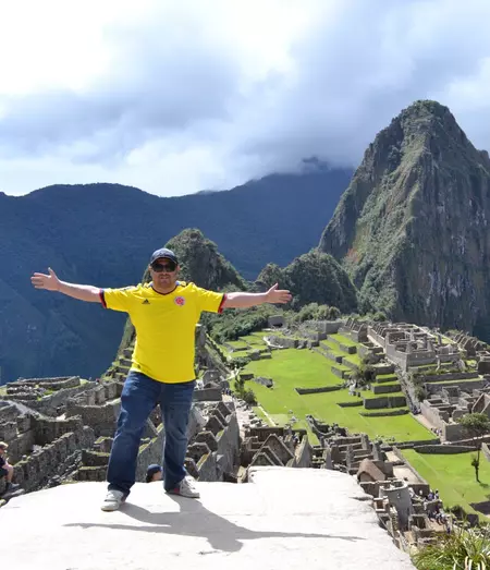 Carlos smiling in front of the Machu Picchu ruins in Peru.