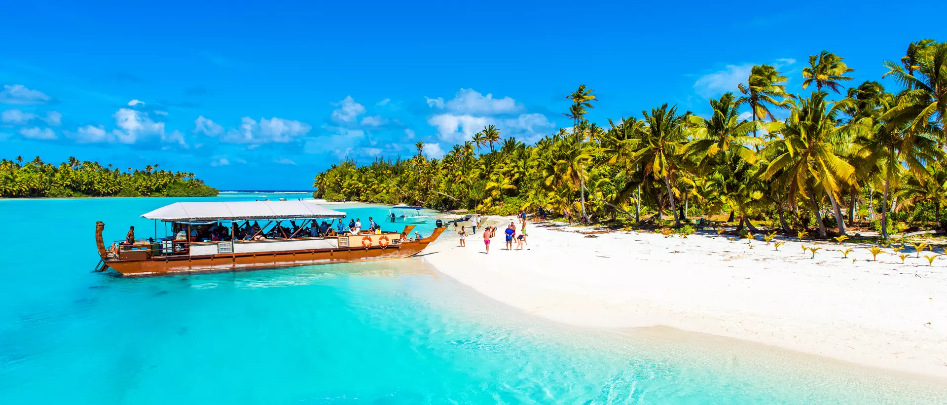 a boat moored next to a white sand beach on a tropical island