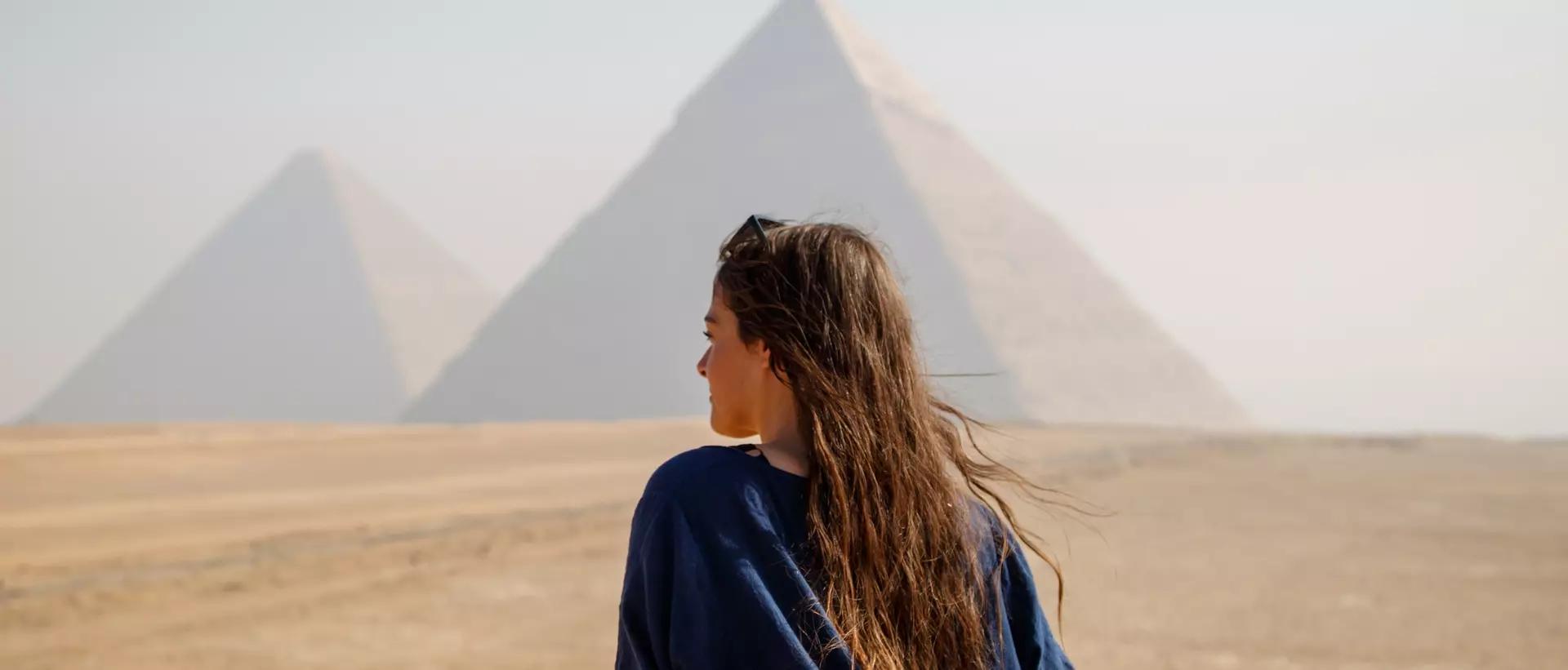 Long-haired woman standing on her back looking at the pyramids of Giza, Egypt