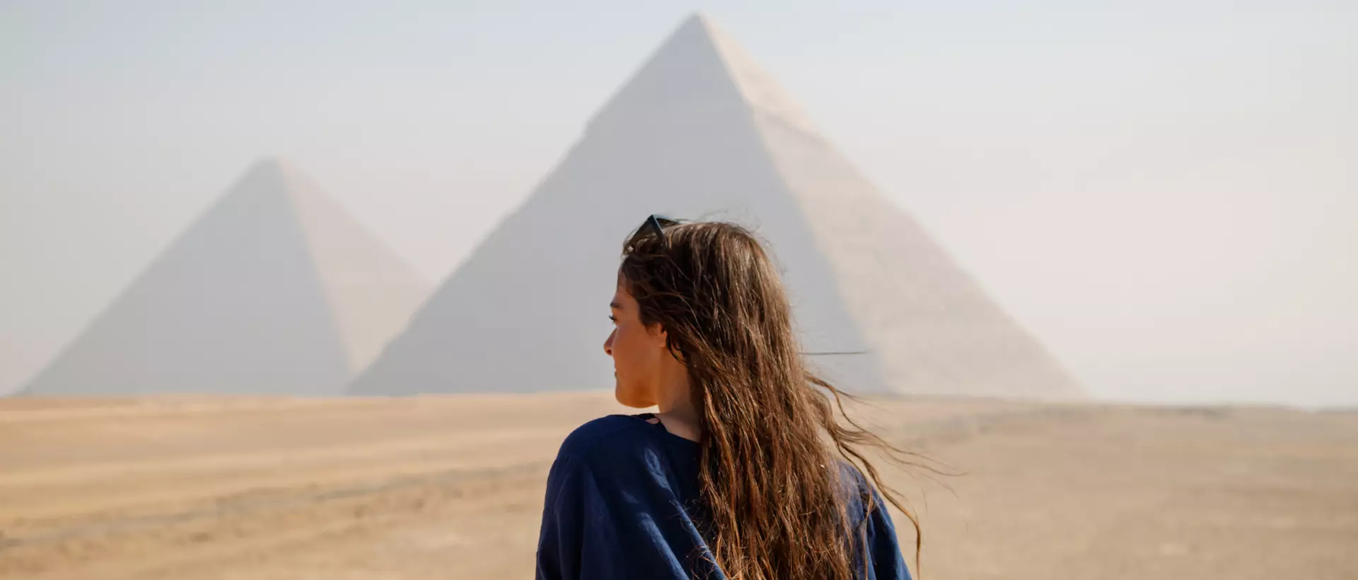 Long-haired woman standing on her back looking at the pyramids of Giza, Egypt