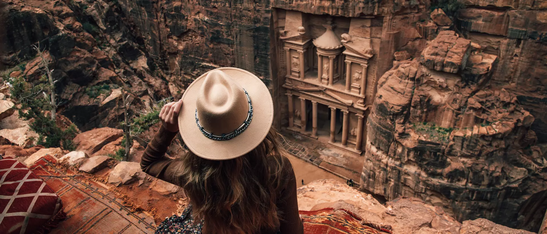 woman sitting on edge of cliff overlooking Petra