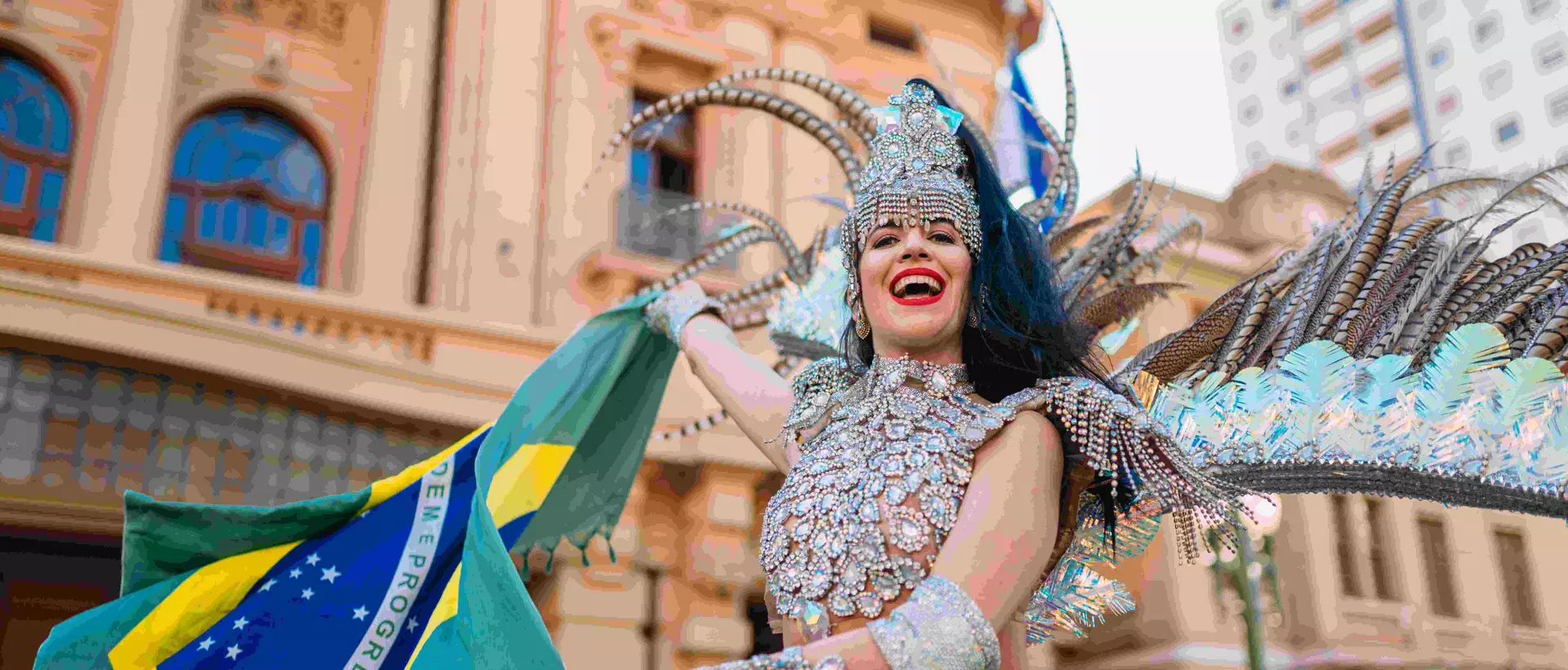 Beautiful Brazilian woman wearing colorful Carnival costume and Brazil flag during Carnaval street parade in city.