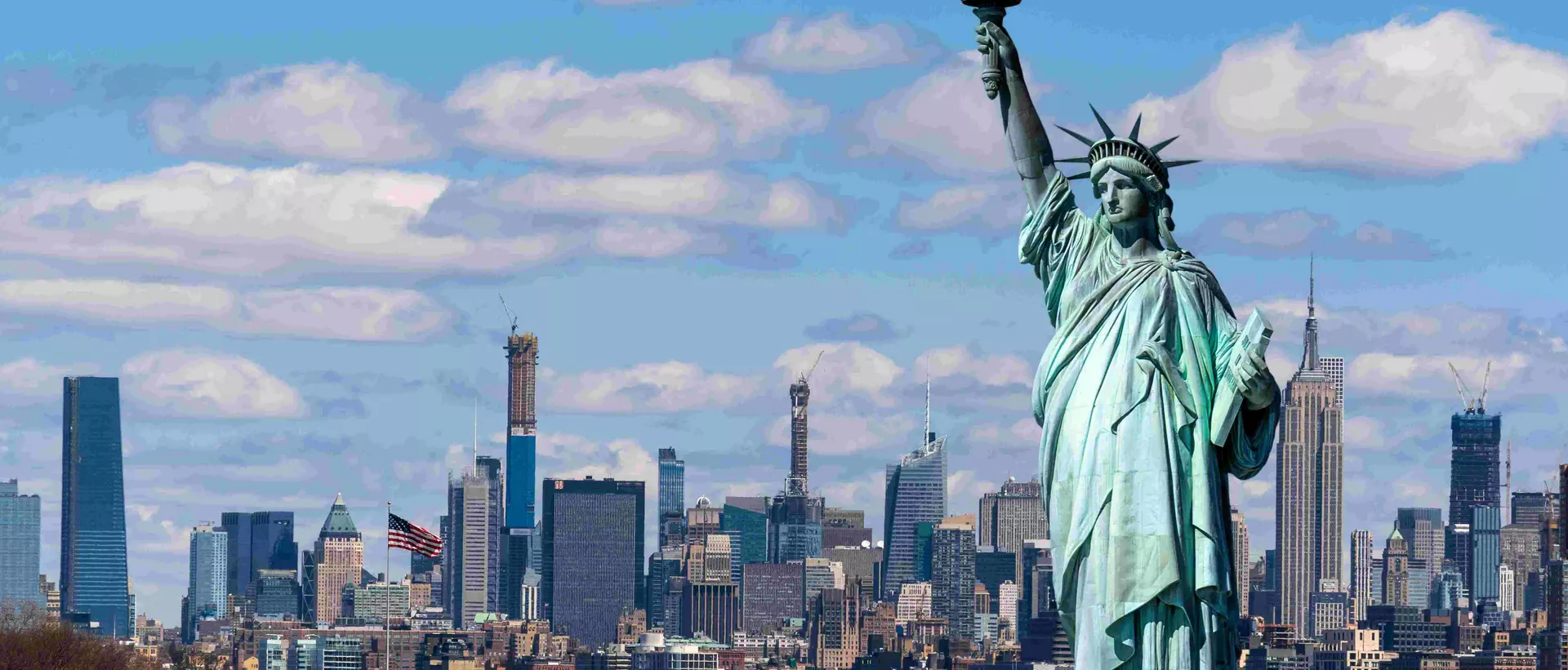 statue of liberty in front of the new york skyline