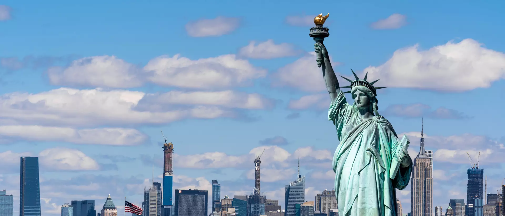 statue of liberty in front of the new york skyline