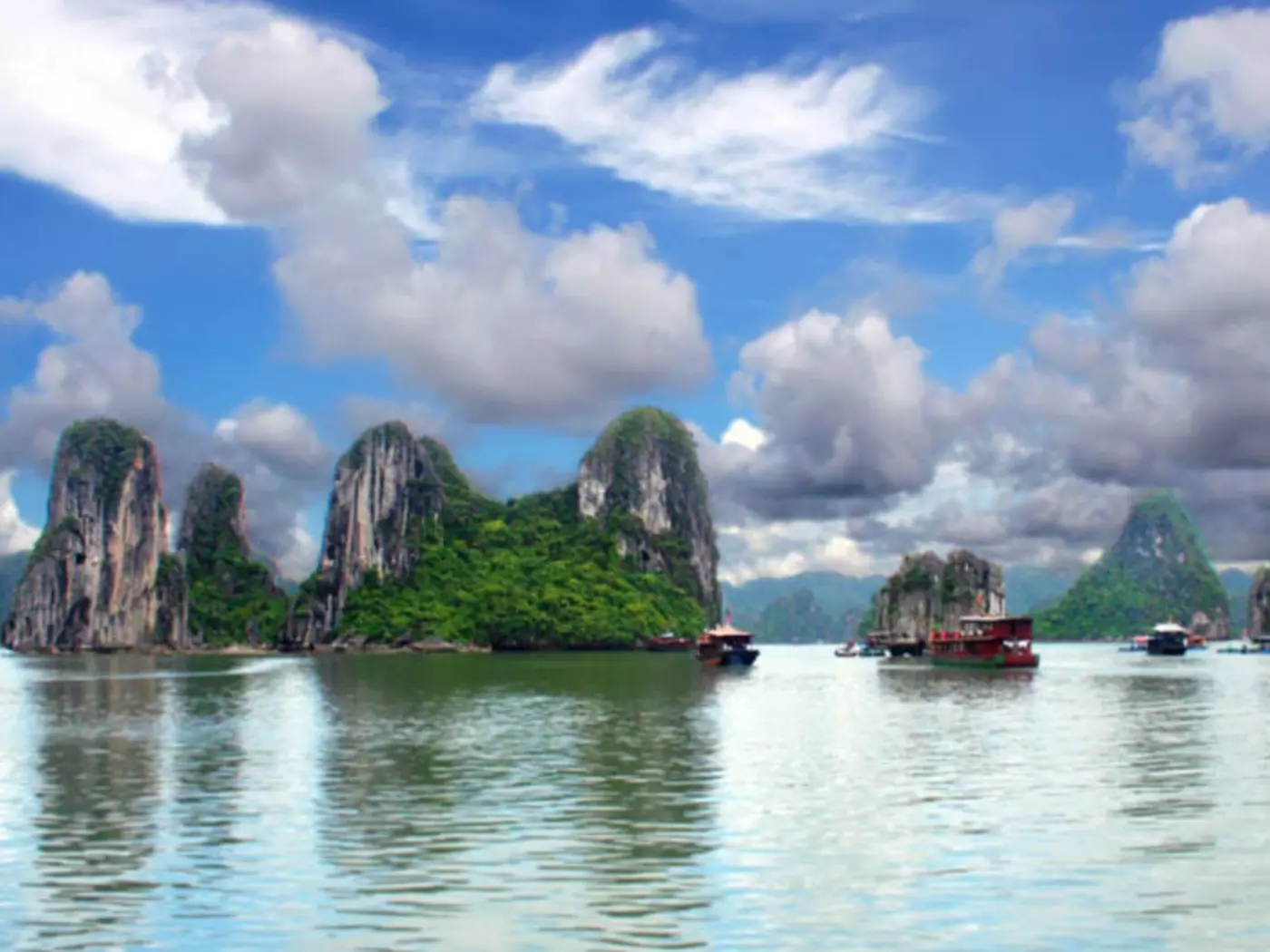 Limestone pillars and tiny islands dot the emerald waters of Halong Bay