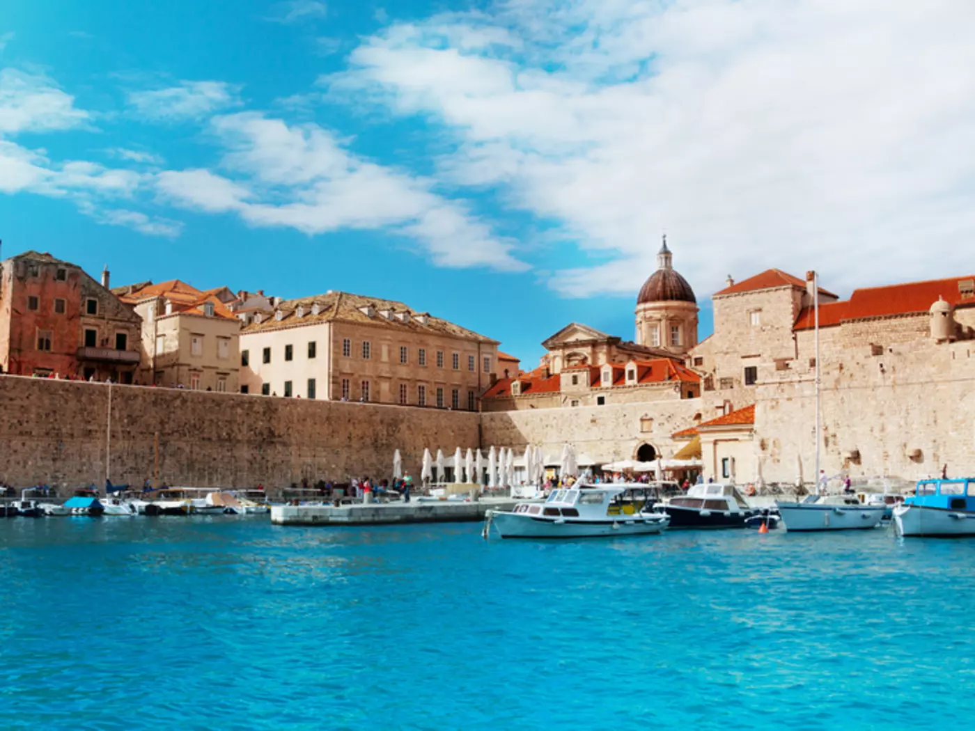 Port of Dubrovnik from water in sunny day with boats parked to the peer