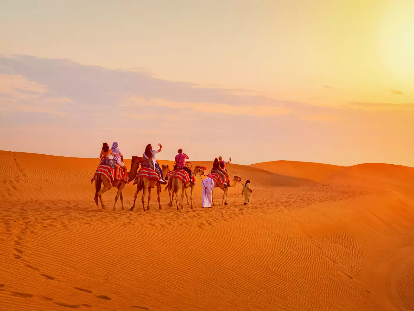 A caravan of camels carrying tourists pass through the sands of the desert around Dubai.