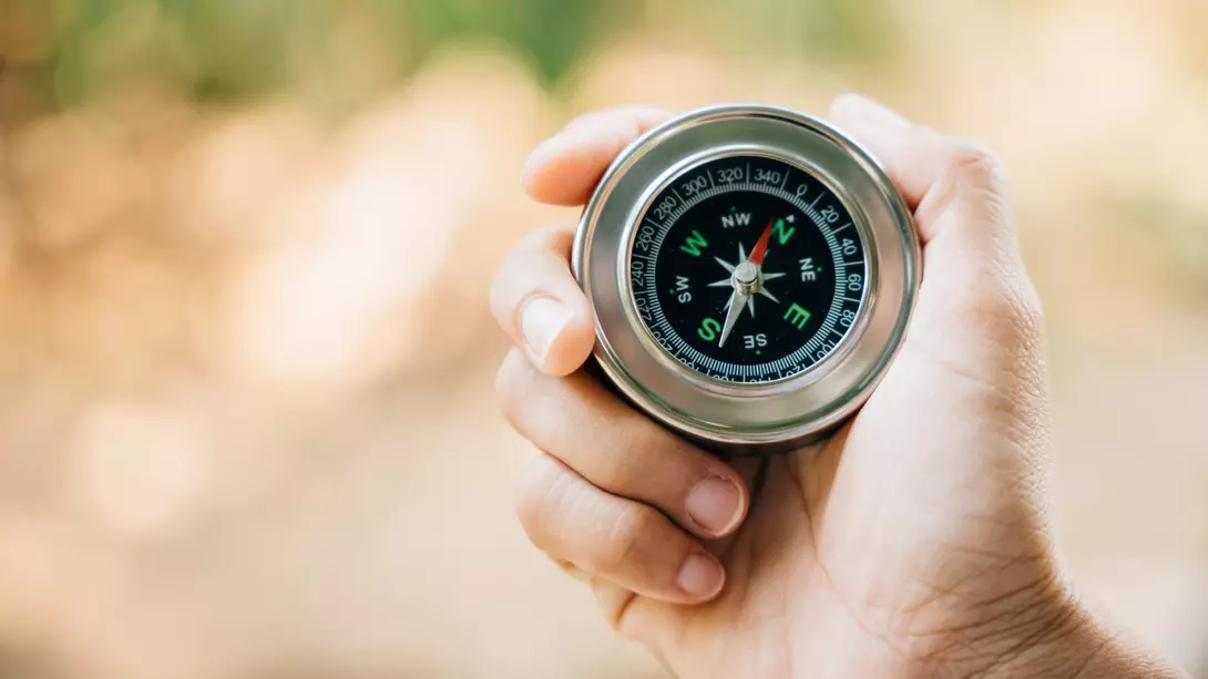Thailand A traveler holding a compass in a park seeks guidance and direction