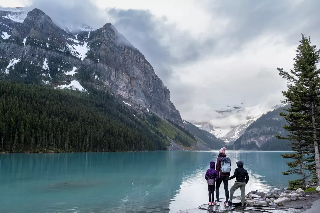 Family hiking around a pristine glacial lake in Banff National Park, Canada.