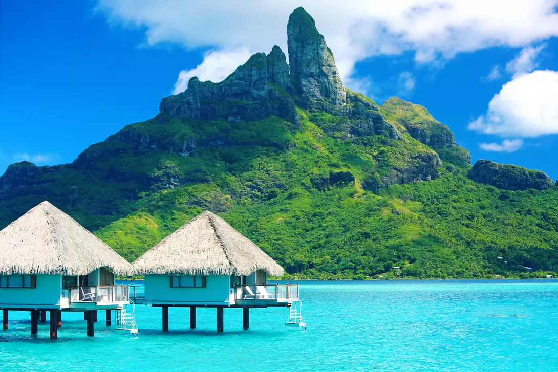 Mt. Otemanu in front of blue water and overwater bungalows in Bora Bora, French Polynesia