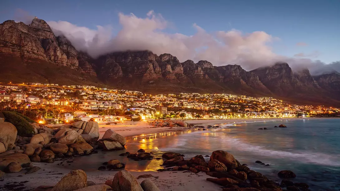 Camps Bay outside Cape Town in South Africa at sunset, as the town lights up and the light fades.