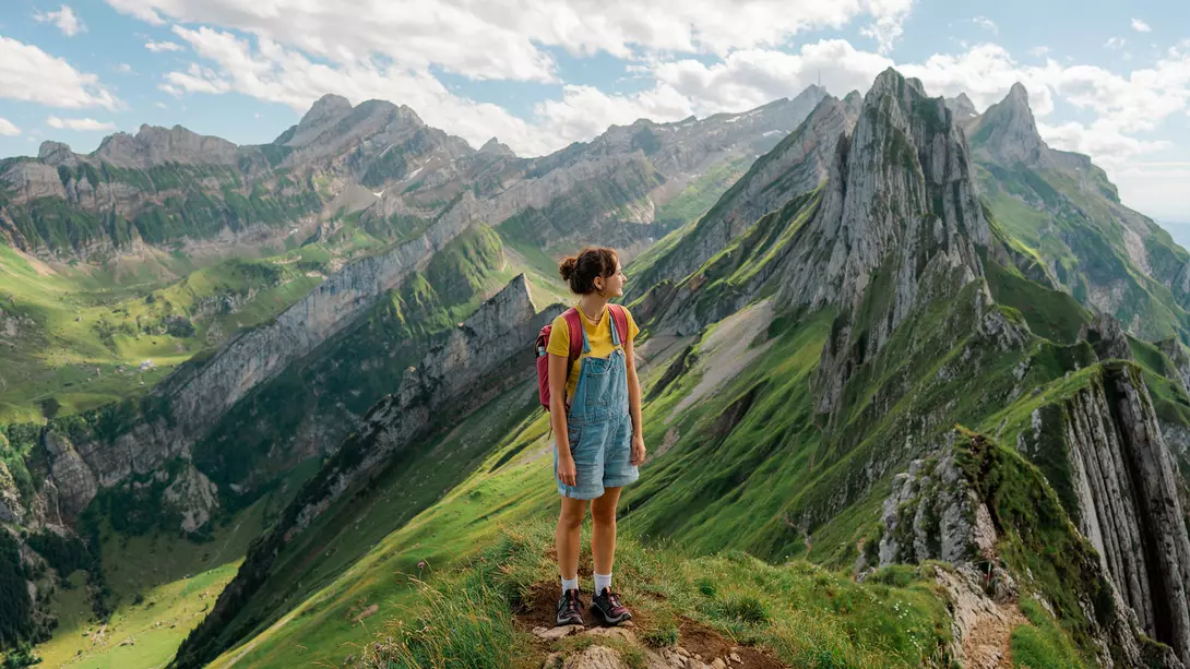 A woman standing on the top of a mountain looking out at vistas in Switzerland.