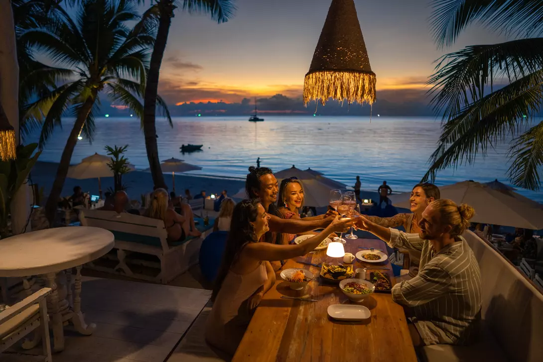 A group of people enjoy a meal at night in a seaside restaurant in Thailand.