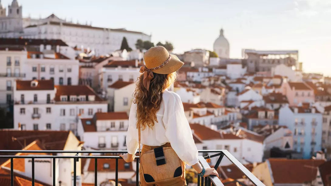 A woman stands looking out over the whitewashed homes of Lisbon, Portugal
