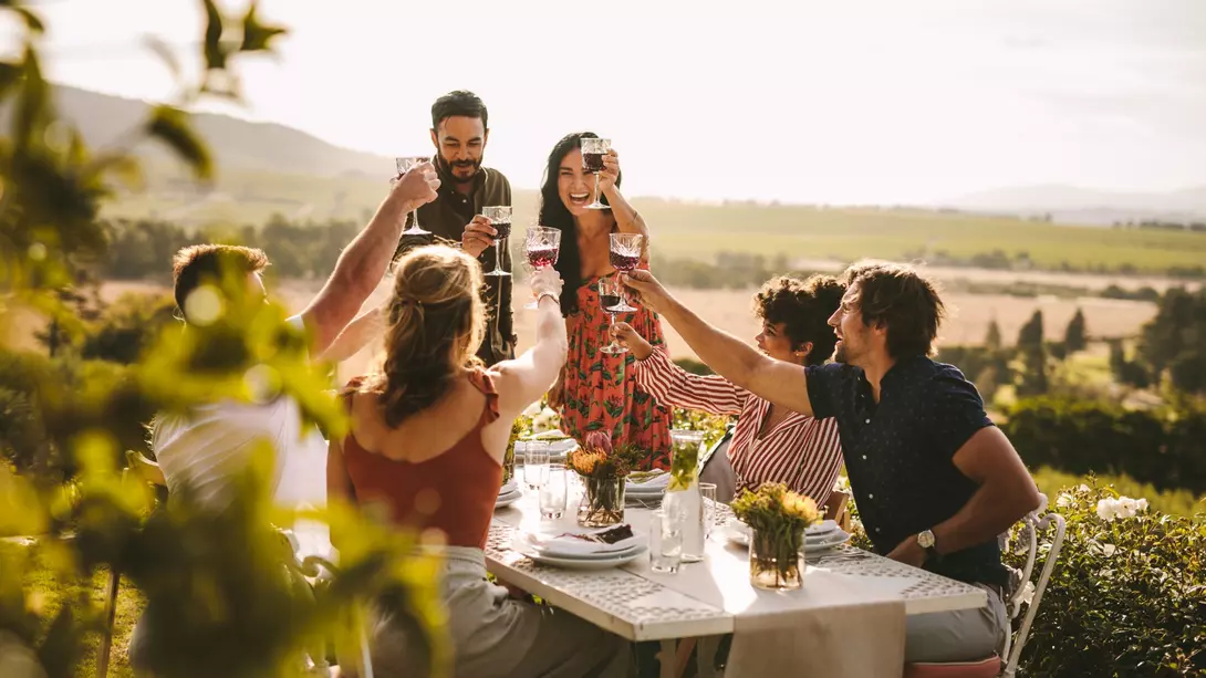 Group of friends toasting wine and enjoying dinner outdoors