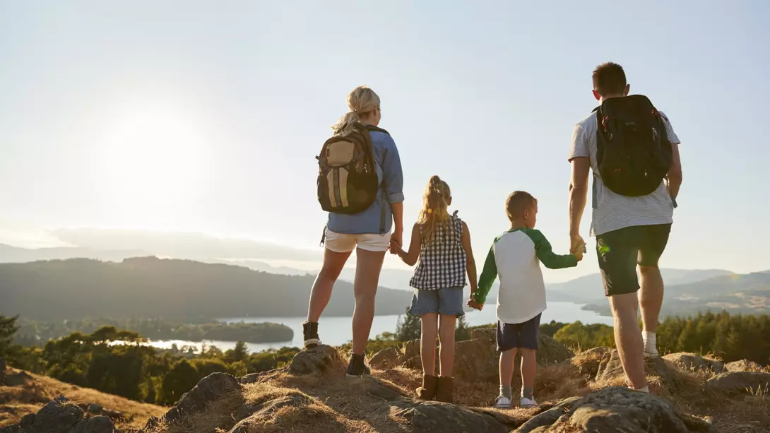 Rear View Of Family Standing At Top Of Hill On Hike Through Countryside In Lake District UK