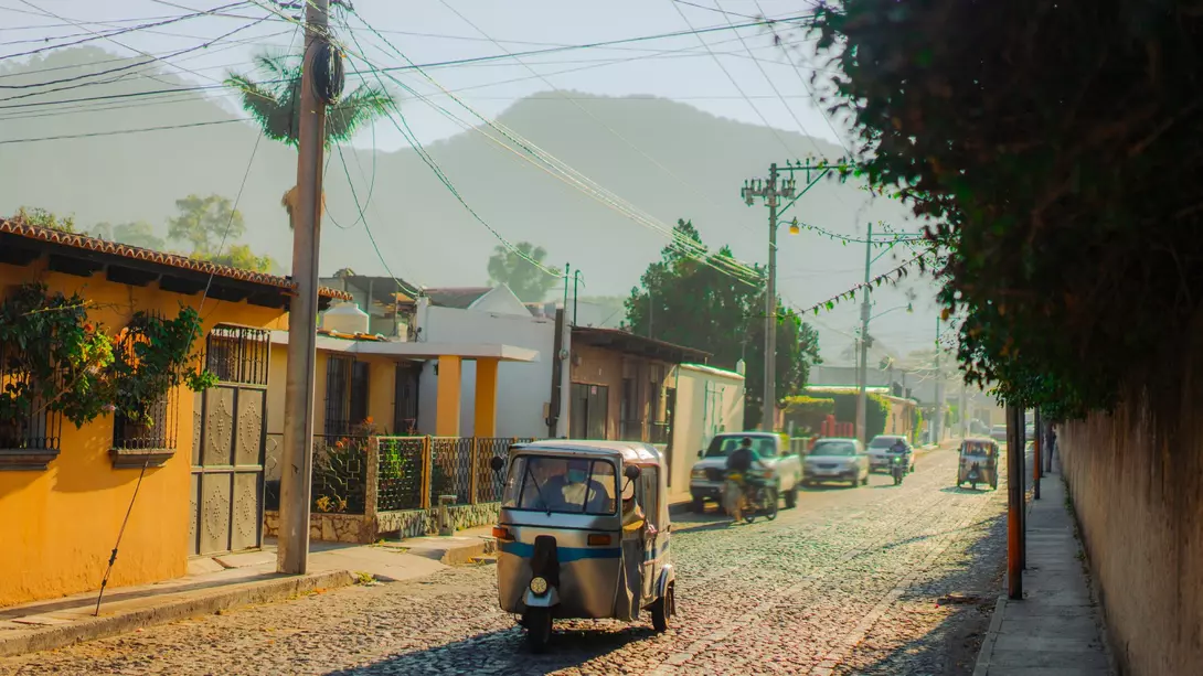 Tuk-tuk three wheeled vehicle driving along historical street in Guatemala