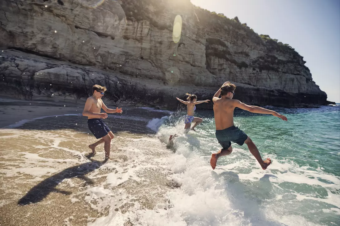 Catania, Italy A bunch of happy teenagers running into the surf in Italy