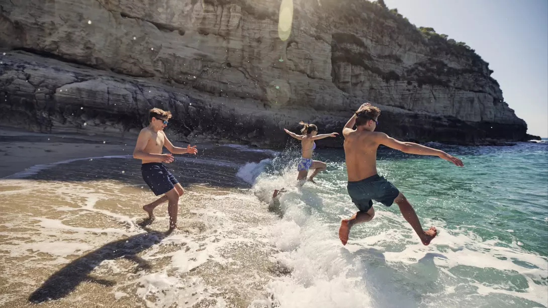 A bunch of happy teenagers running into the surf in Italy