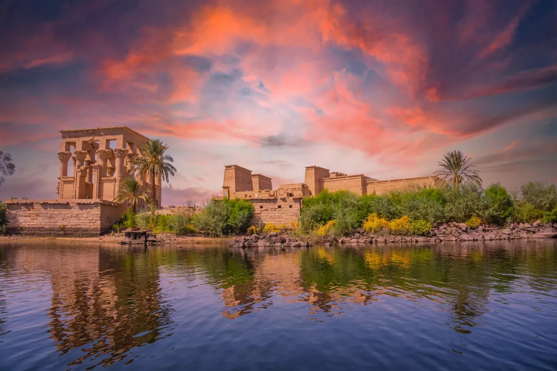 Incredible orange sunrise at the temple of Philae, a Greco-Roman construction seen from the Nile river, a temple dedicated to Isis, goddess of love