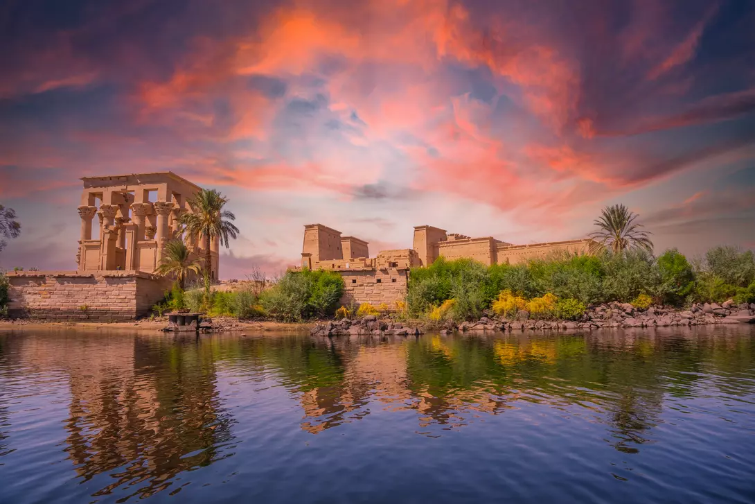 Incredible orange sunrise at the temple of Philae, a Greco-Roman construction seen from the Nile river, a temple dedicated to Isis, goddess of love