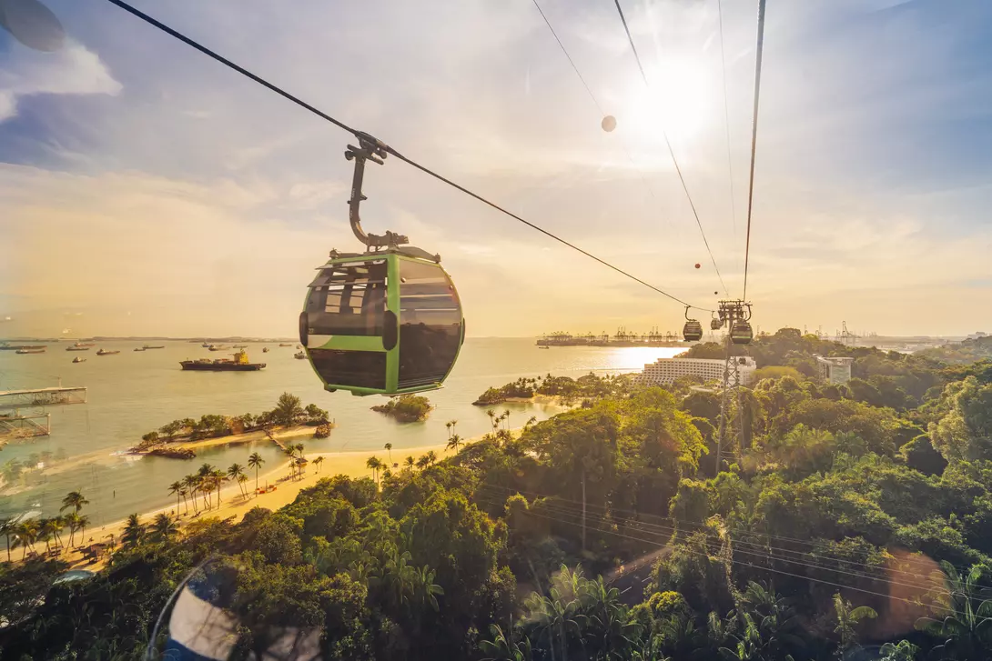 Cable car trip to Sentosa Island, Singapore. Aerial view showing lush green forest and sandy beach below