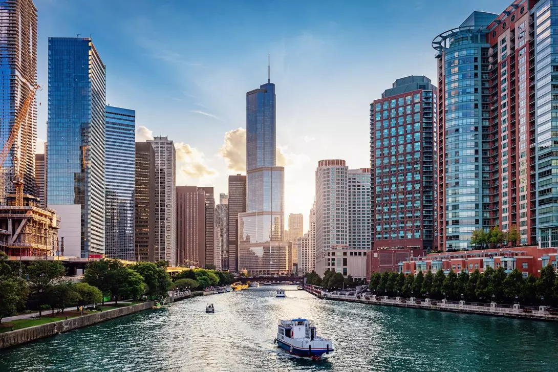 Cityscape from Chicago River Waterfront at Dusk. Small boats and tourist ferries cruising towards the Michigan Lake