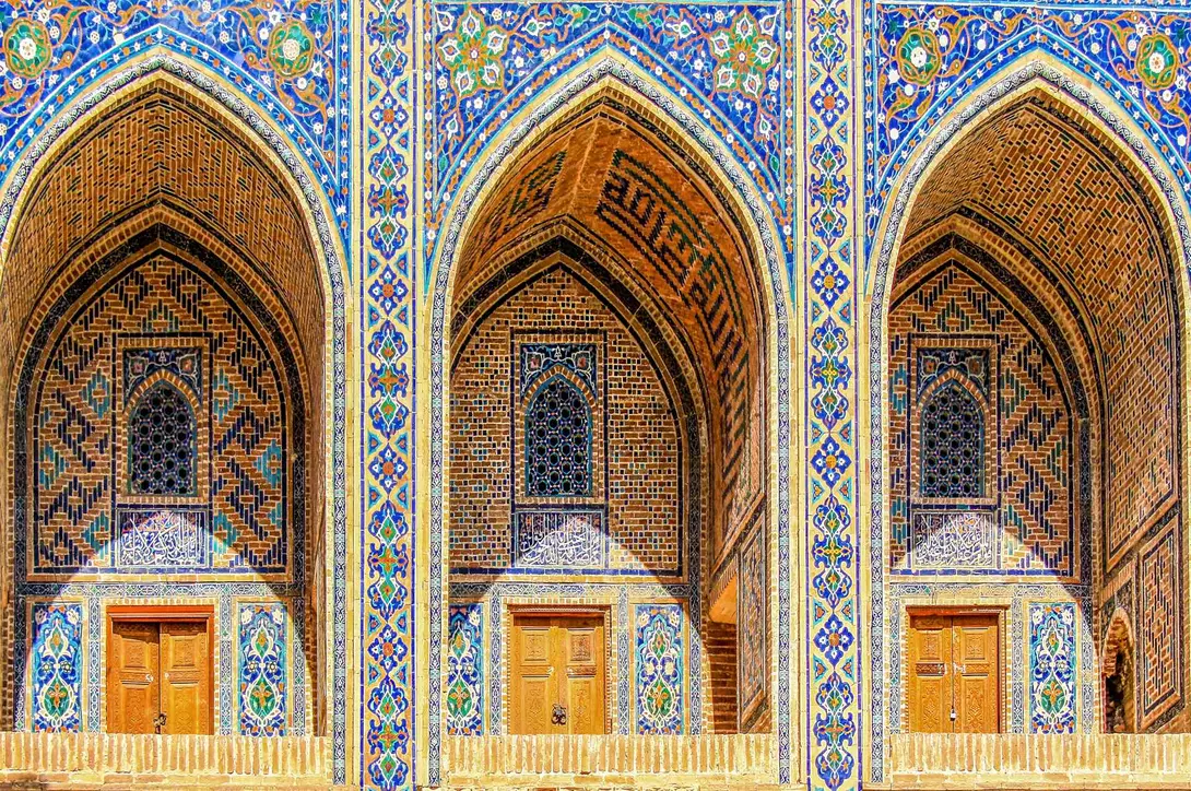 Sherdor Madrassah facade with blue, yellow and green tiles, wall with tall arches and windows