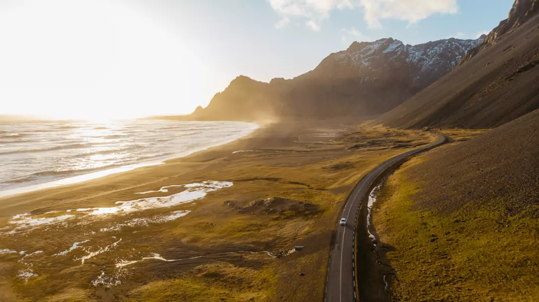 Uncover the magic of Iceland on your next road trip. Aerial view of a car driving on scenic road in Iceland