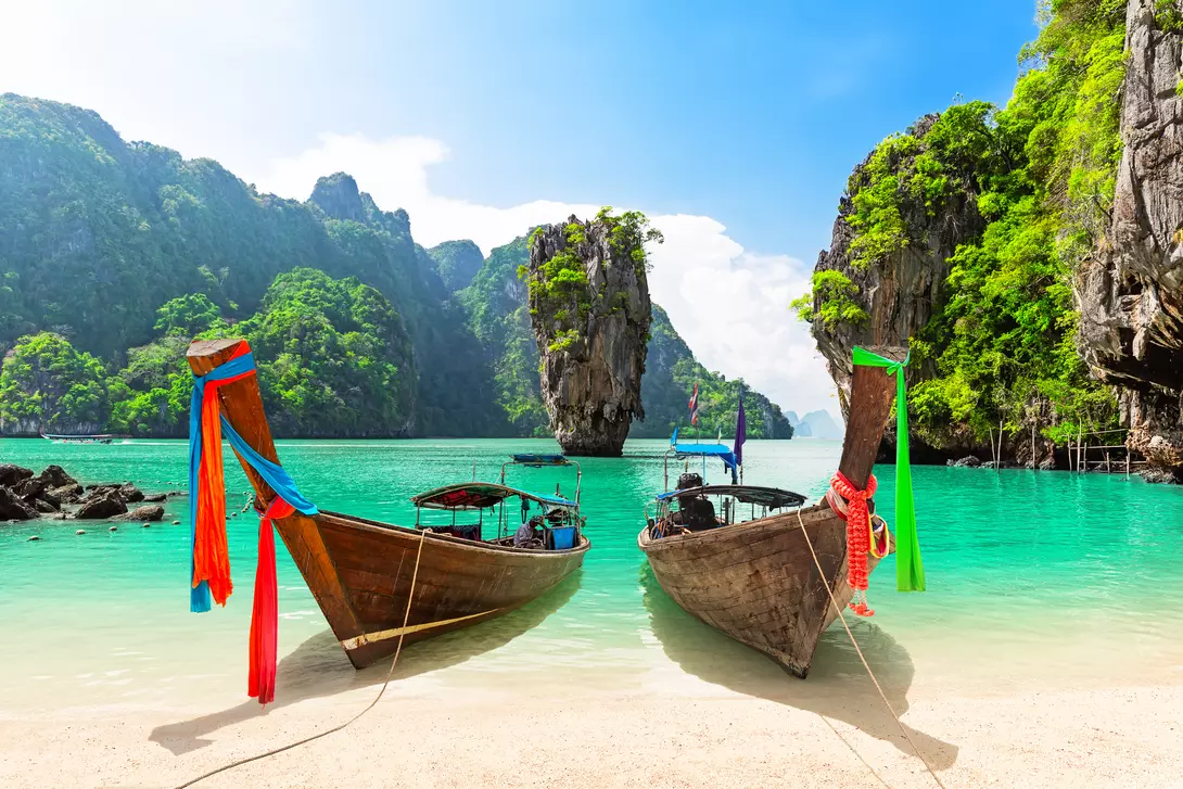 James Bond island with thai traditional wooden longtail boat and beautiful sand beach in Phang Nga bay, Thailand