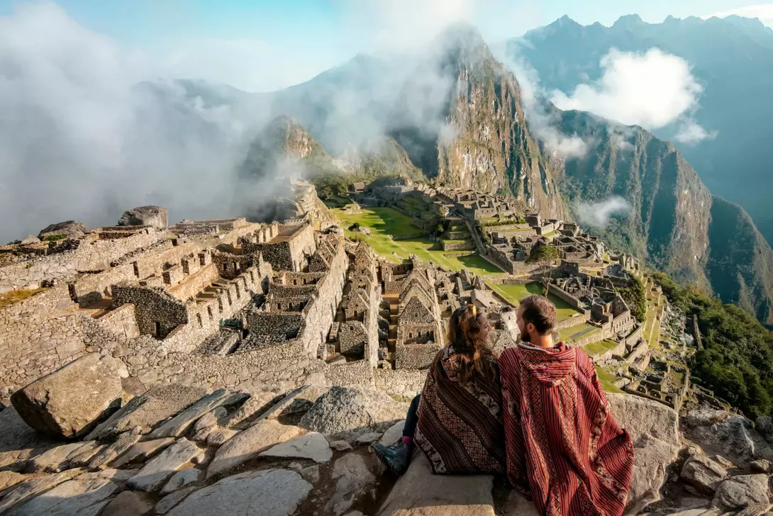 A couple sits atop the ancient Machu Picchu