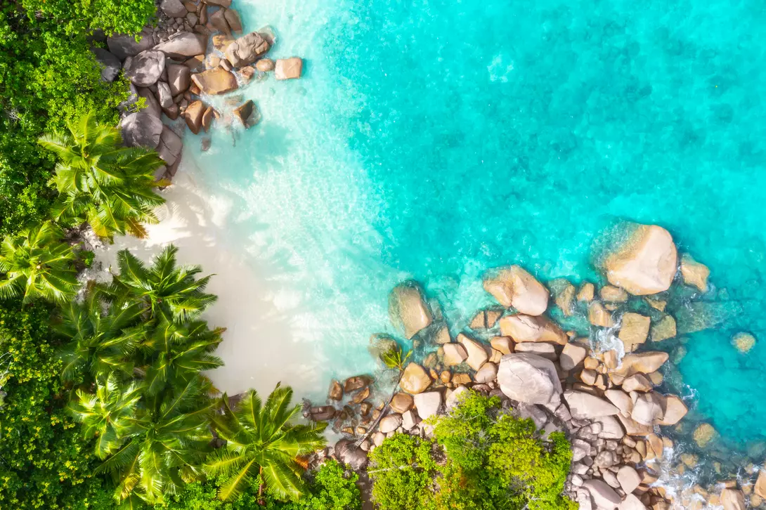 Aerial view from above of beach and bright blue waters of coastline