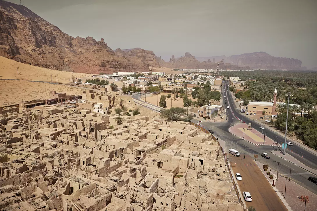 "Elevated view Al-Ula centuries-old mudbrick heritage site, lush green date palm groves, and sandstone rock formations "