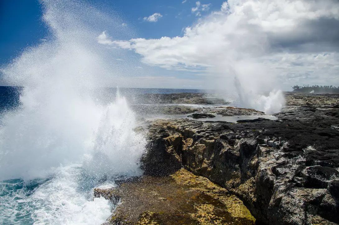 The Alofaaga Blowholes send water towards the bright blue sky along the ocean in Somoa