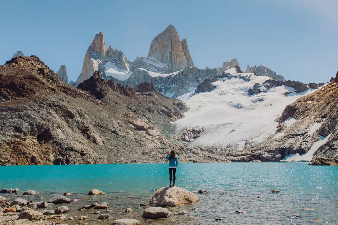 Female explorer hiking to the turquoise glacial lagoon with view of Mount Fitz Roy in El Chalten, Argentina
