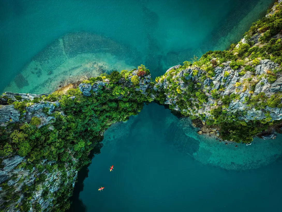 Drone view on rocks and canoes floating on turquoise water in the Halong Bay,