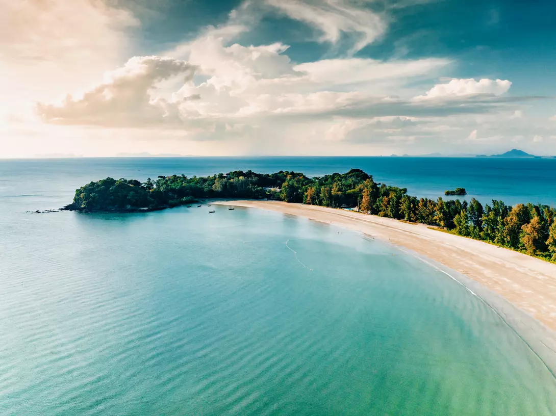 Aerial point of view towards the island bay and coast under sunny blue summer sky.