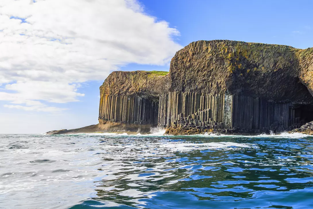 Magnificent rock formations and caves rising from the ocean against cliffside