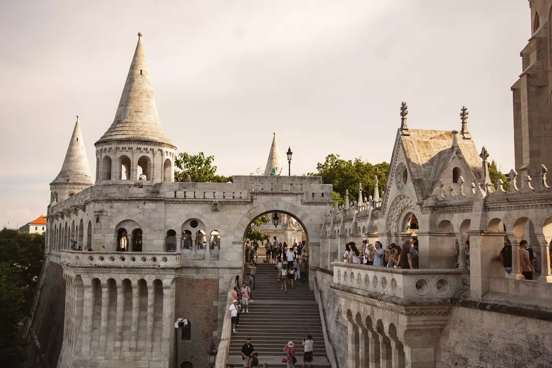 Hungarian Fisherman's Bastion with gothic towers, steps, and visitors under a cloudy sky.