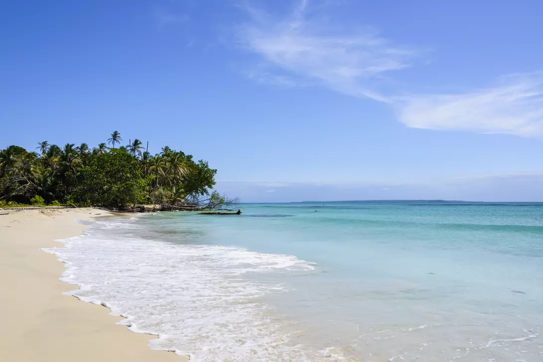 White sand beach on a tropical island surrounded by a turquoise sea.