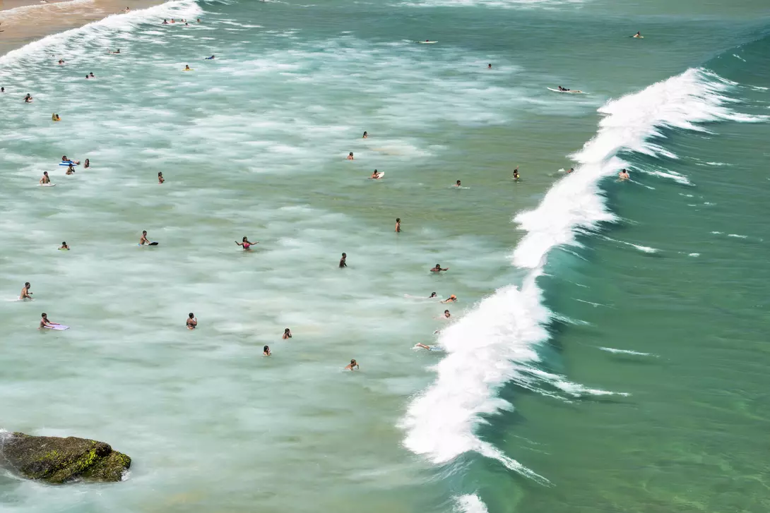 Aerial view of people swimming and surfing as the swell reaches the coastline Geribá Beach in Búzios