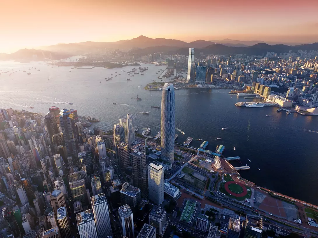 "Dramatic skyline of Hong Kong Island and busy ships navigates across the Victoria Harbour during beautiful sunset "