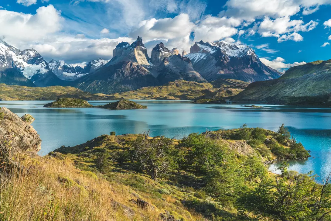 Blue lake on a snowy mountains background and cloudy sky